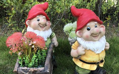 公園草坪上兩個玻璃鋼彩繪卡通背竹筐和推花盆小推車的小矮人雕塑